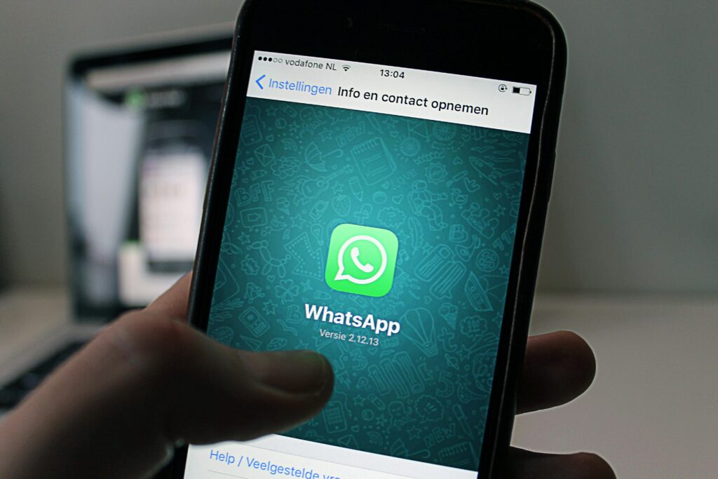 Current image: A smartphone displaying the WhatsApp application screen held by a person.